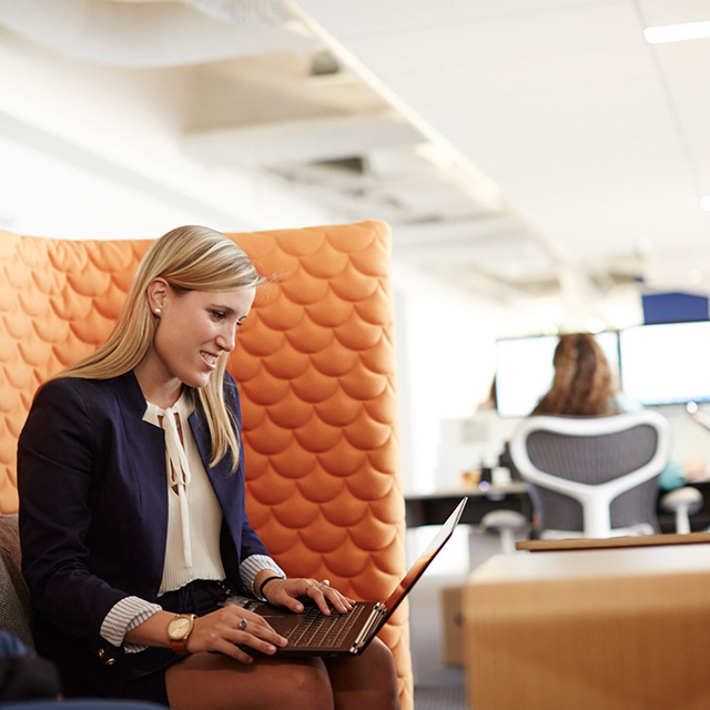 Woman with a laptop sitting on a couch.