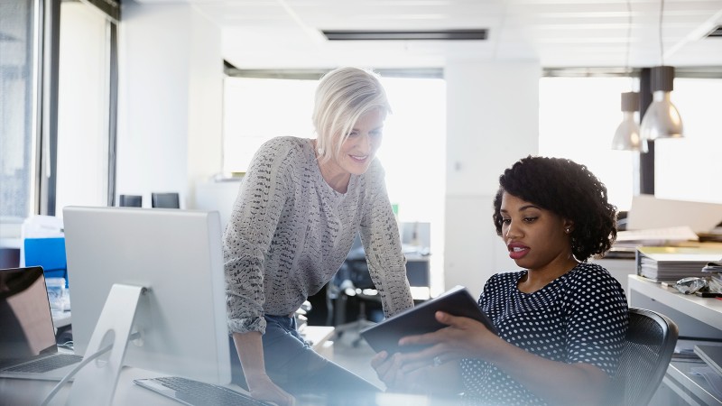 Women in an office at a desk using a tablet